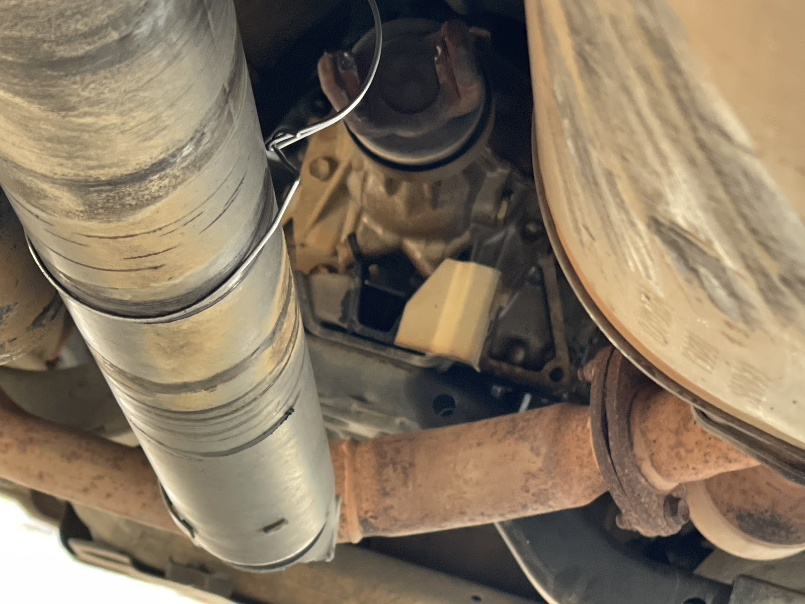 Looking up at the underside of a customer's vehicle during a rear driveline repair, driveshaft and exhaust covered in desert dust